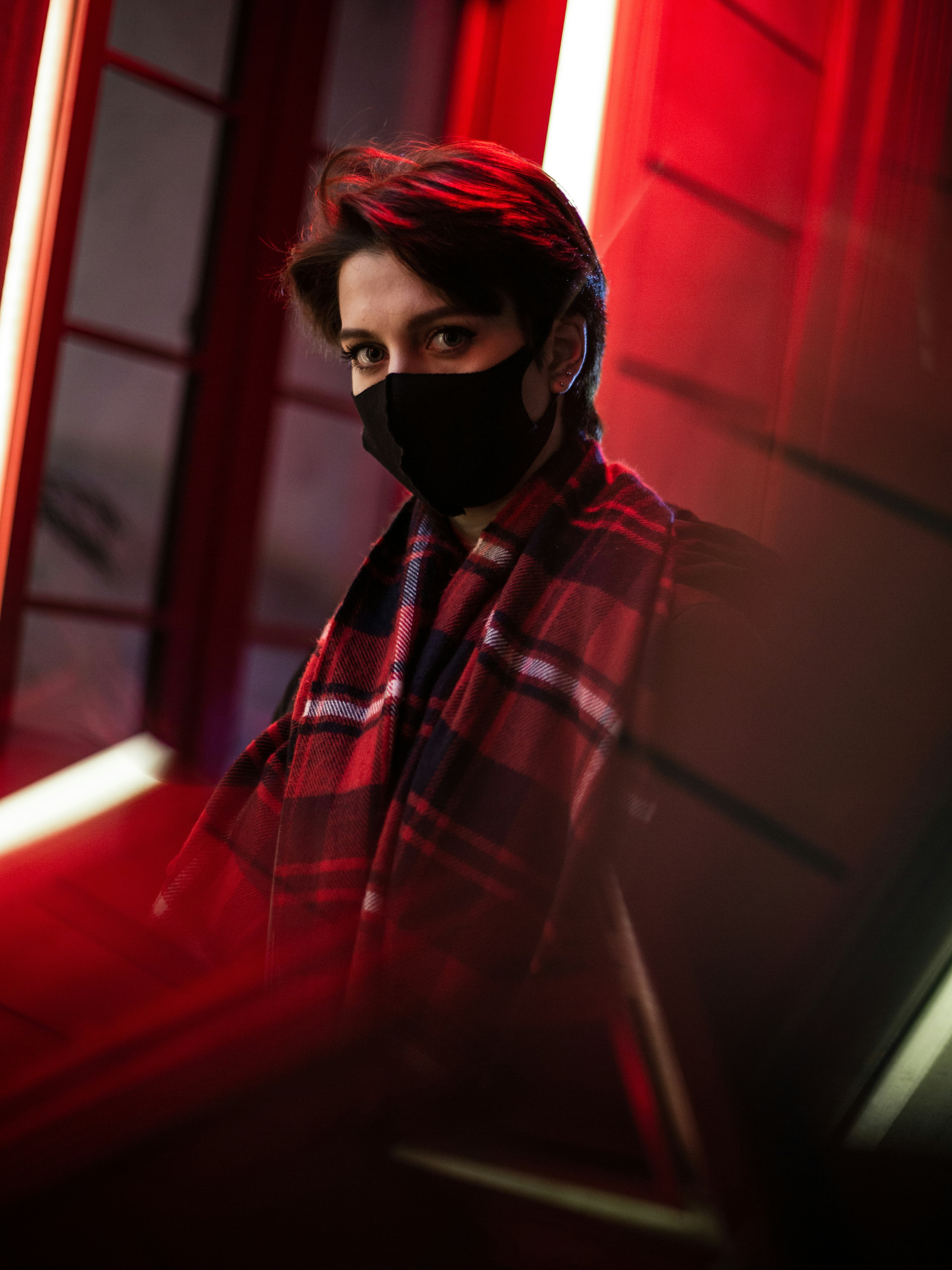 woman in red and black plaid scarf and black mask